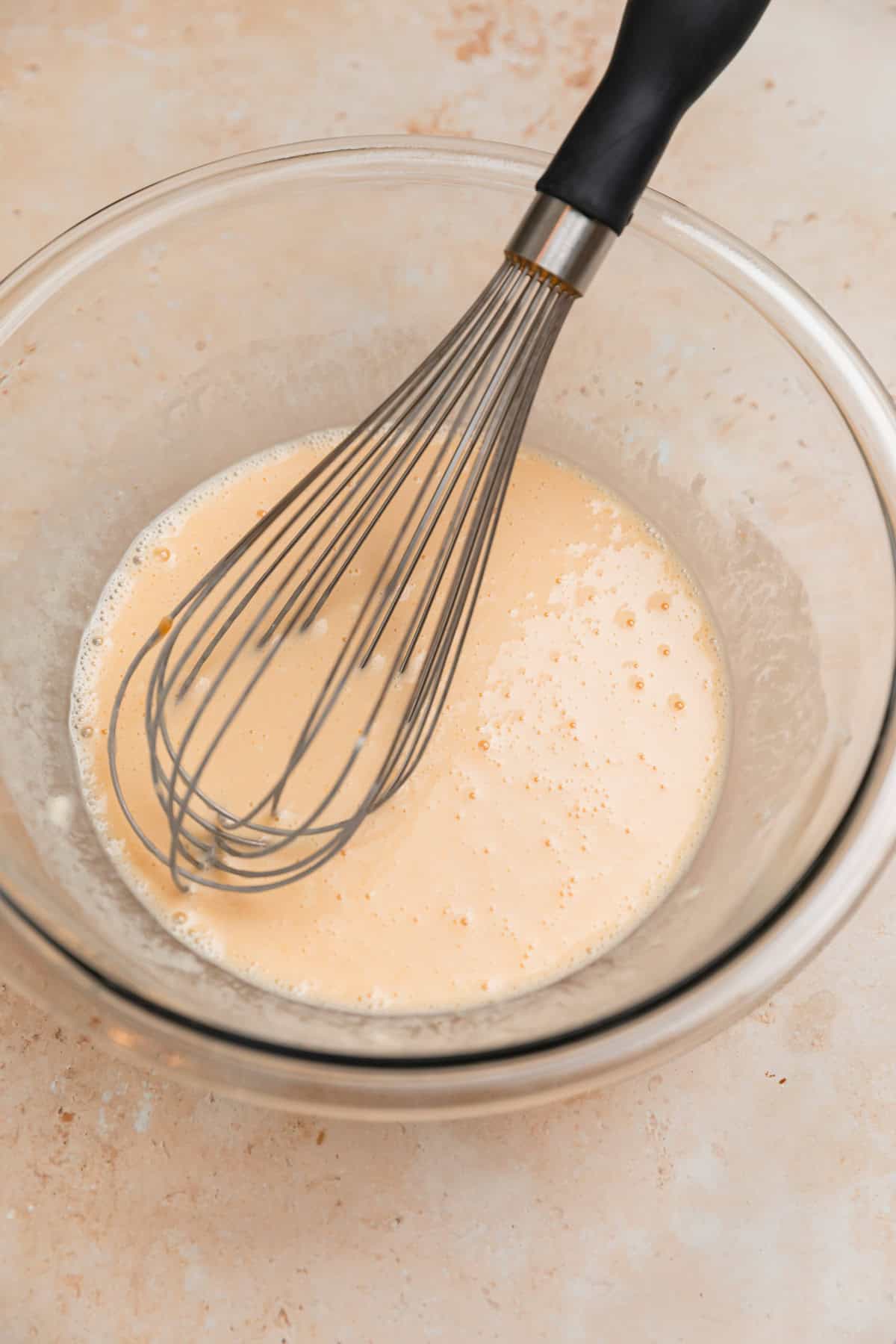 Whisk in bowl with donut ingredients.
