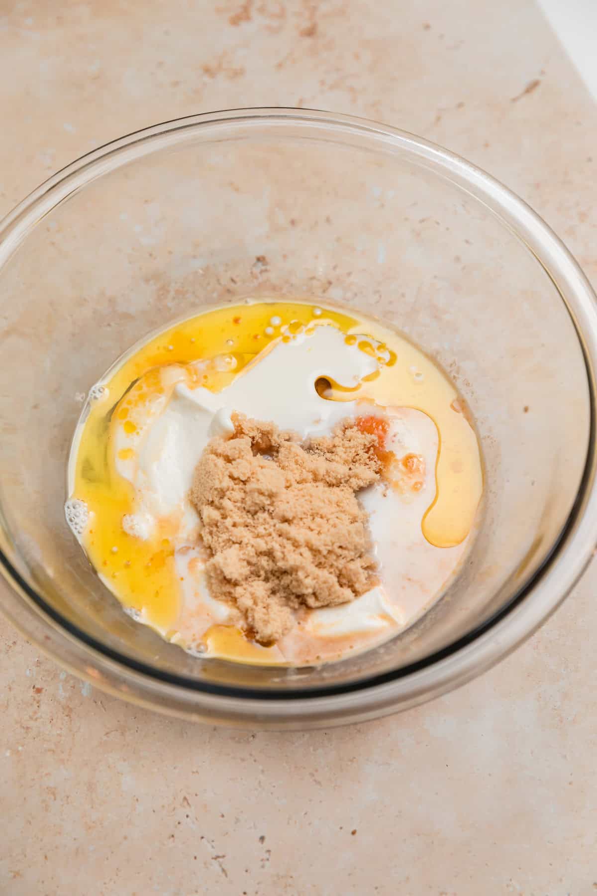 Egg, brown sugar, milk, vanilla yogurt and vanilla in glass bowl.