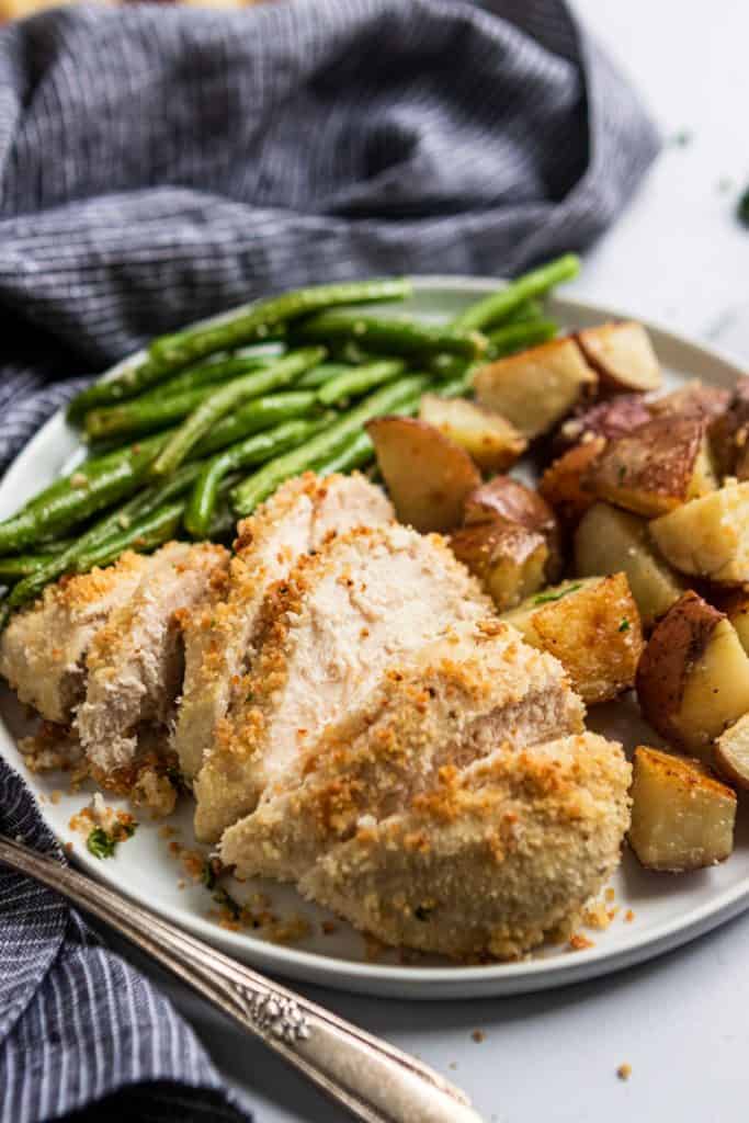 Parmesan Crusted Chicken Dinner on plate with potatoes and green beans.
