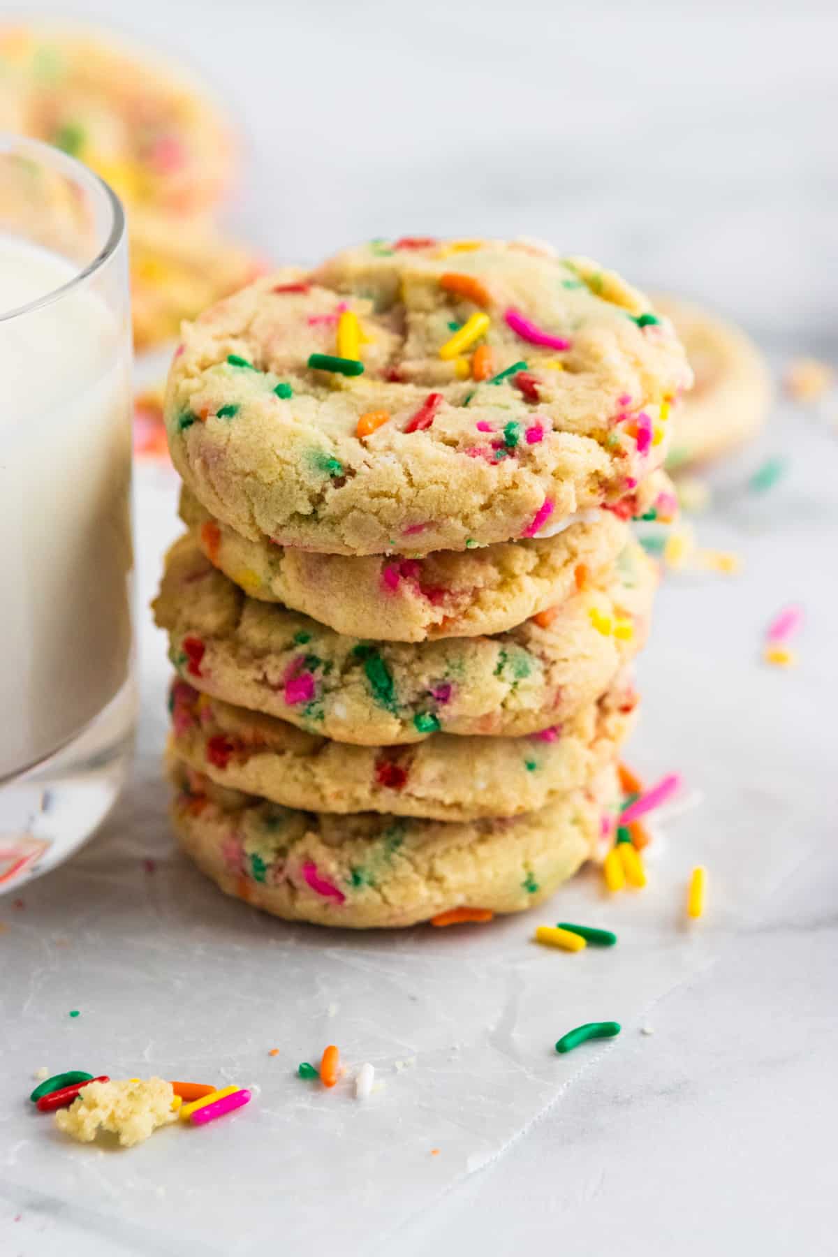 Stack of sugar cookies with rainbow sprinkles with milk.