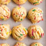 Cookie scoops with funfetti sprinkles on cookie sheet.