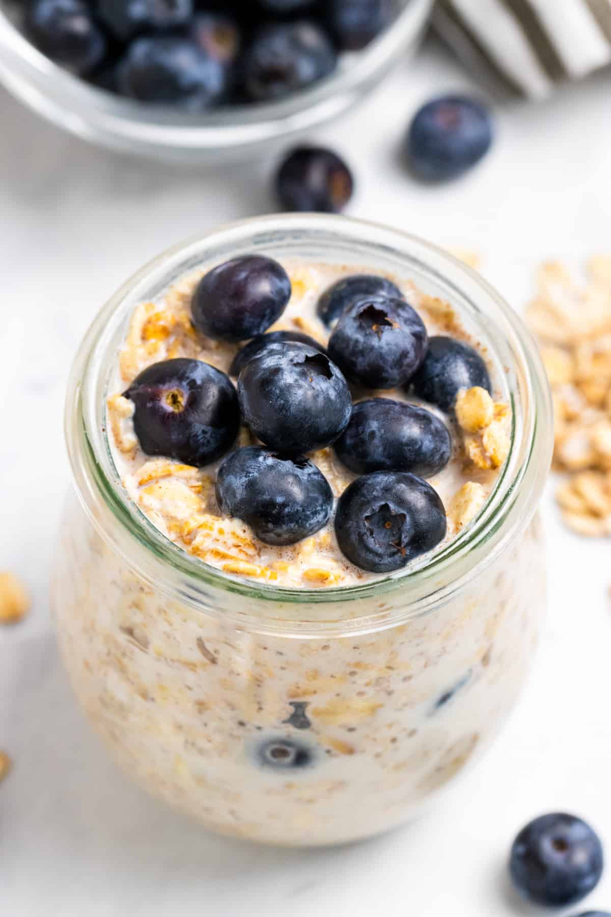 Blueberry overnight oats in glass jar with blueberries on top.