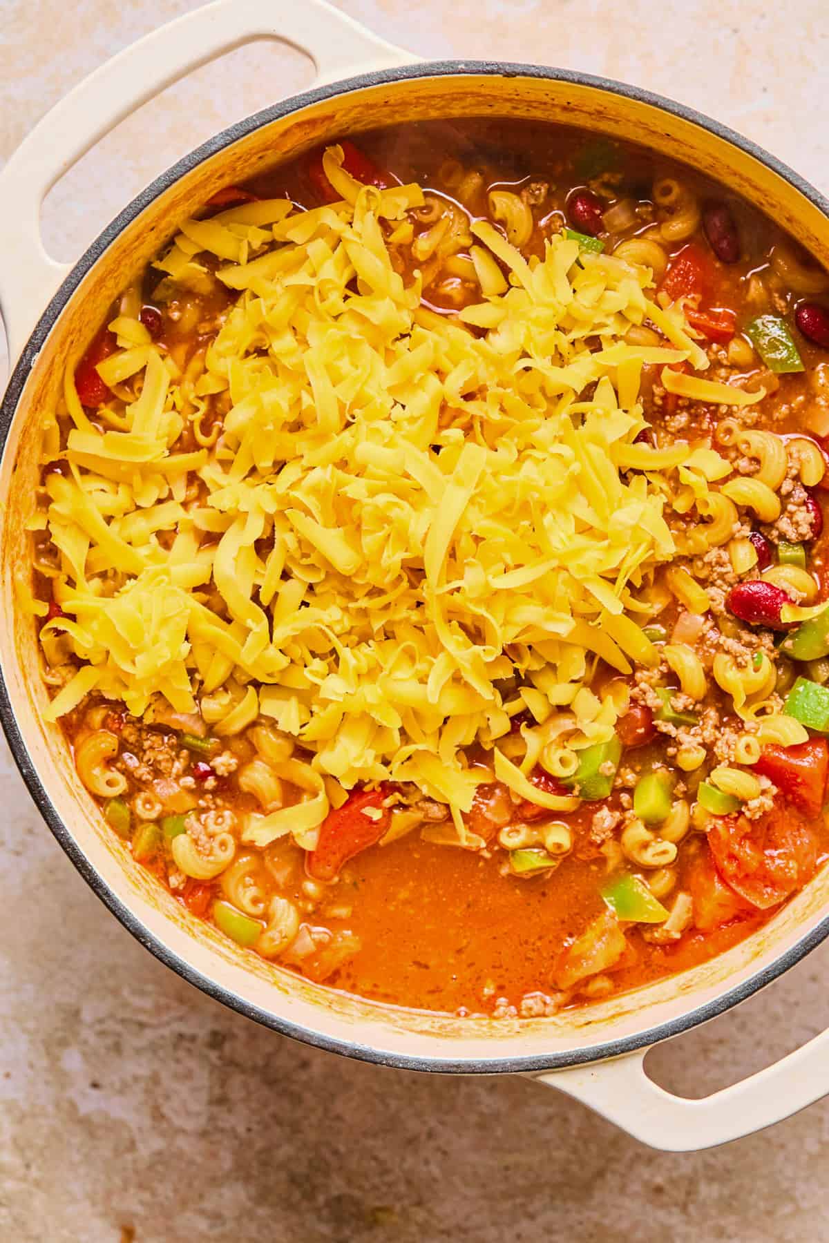 Cheese added to pot of chili and macaroni.