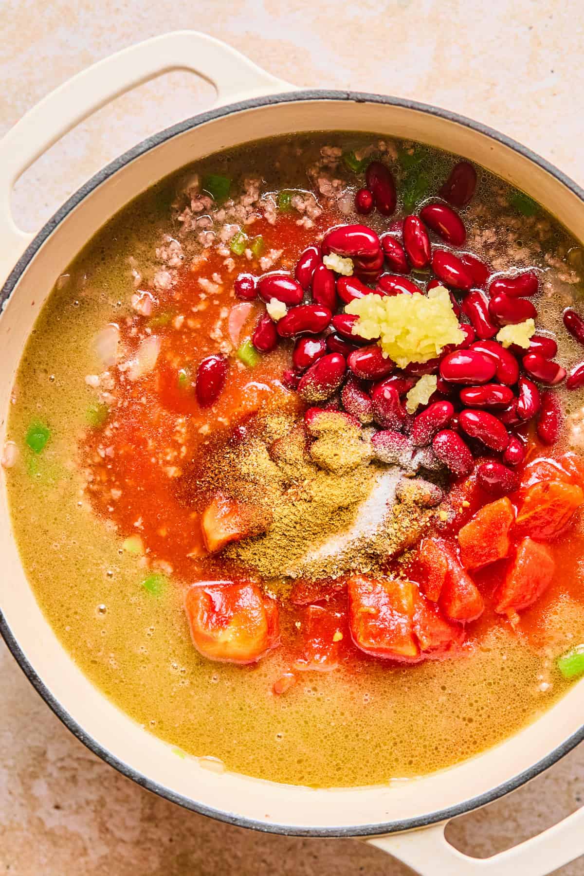 Beans, tomatoes, broth and other ingredients added to dutch oven.