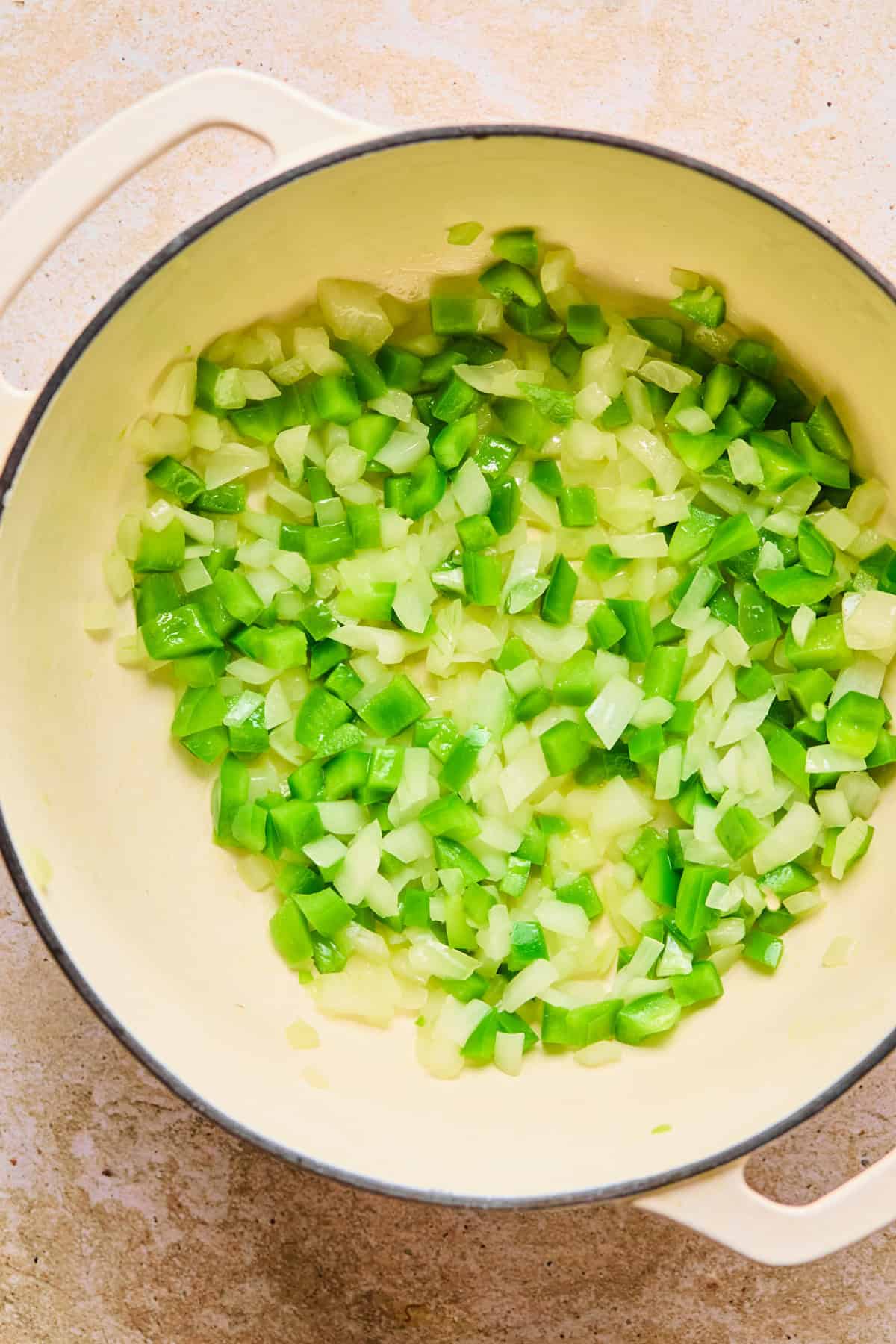 Onion and green bell pepper sautéed in pot.