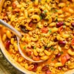 Ladle scooping up chili macaroni and cheese in pot.