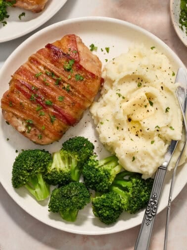 White plate with pork chop dinner including mashed potatoes and broccoli.