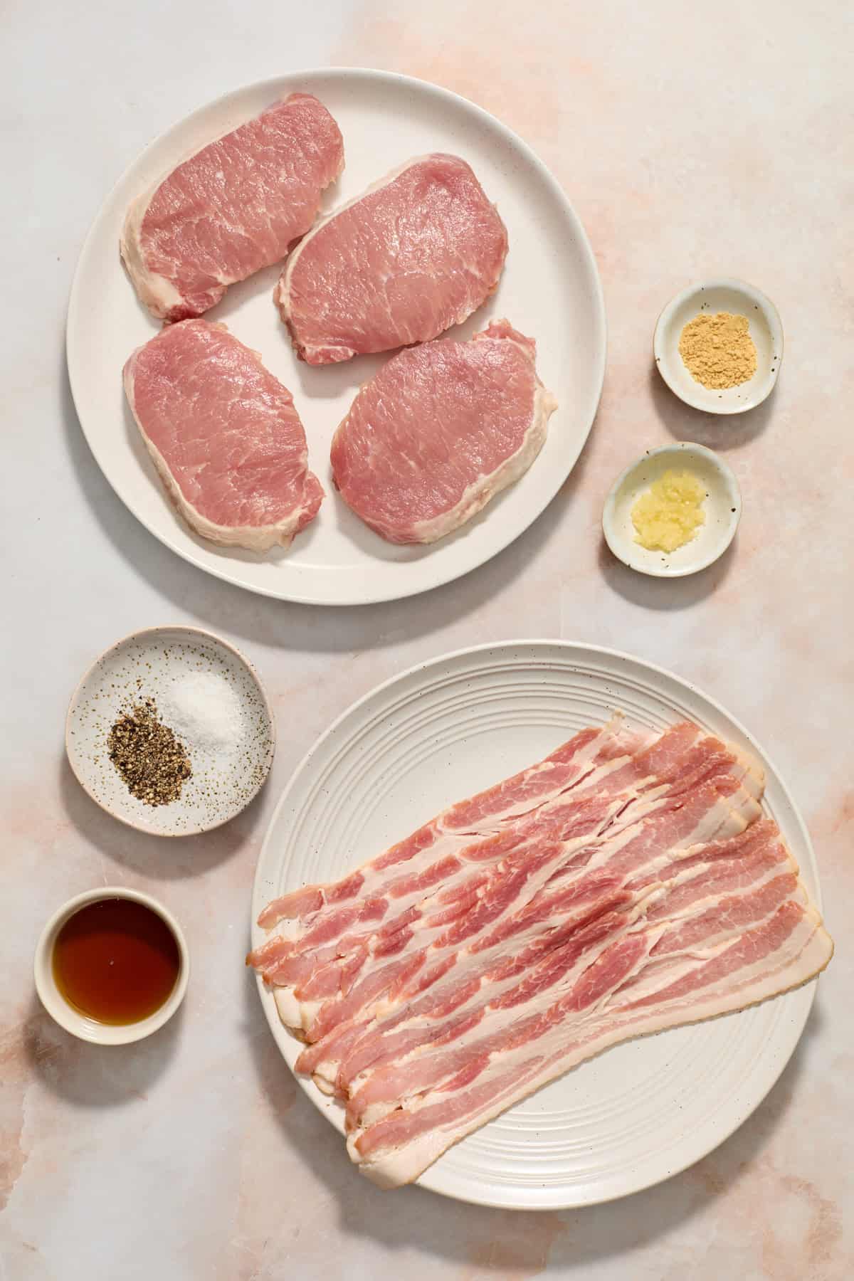 Pork chops, bacon, syrup and other ingredients arranged on surface.