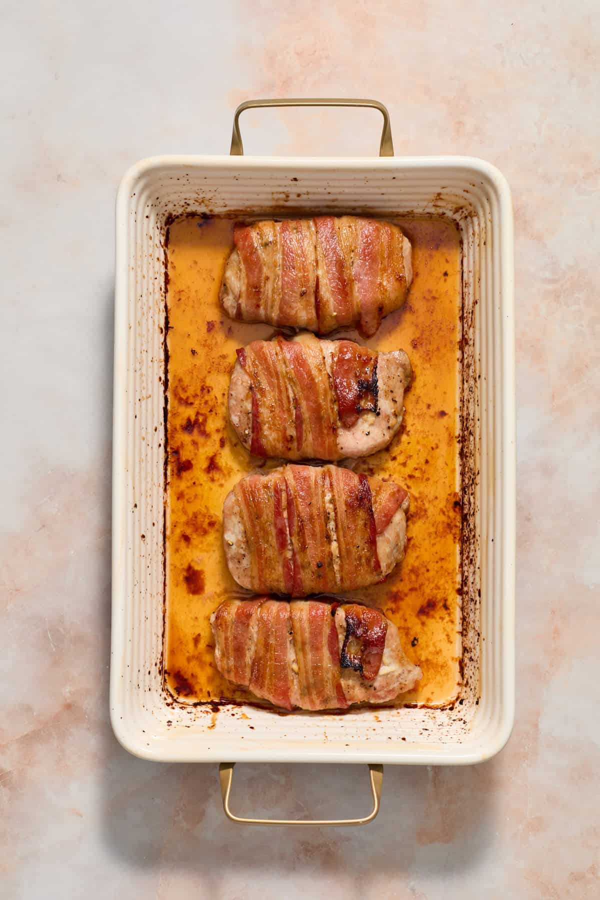 Baked maple bacon wrapped pork chops in baking dish.