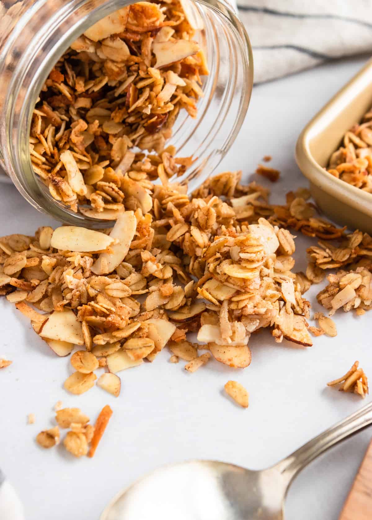 Jar of granola poured out next to baking sheet.