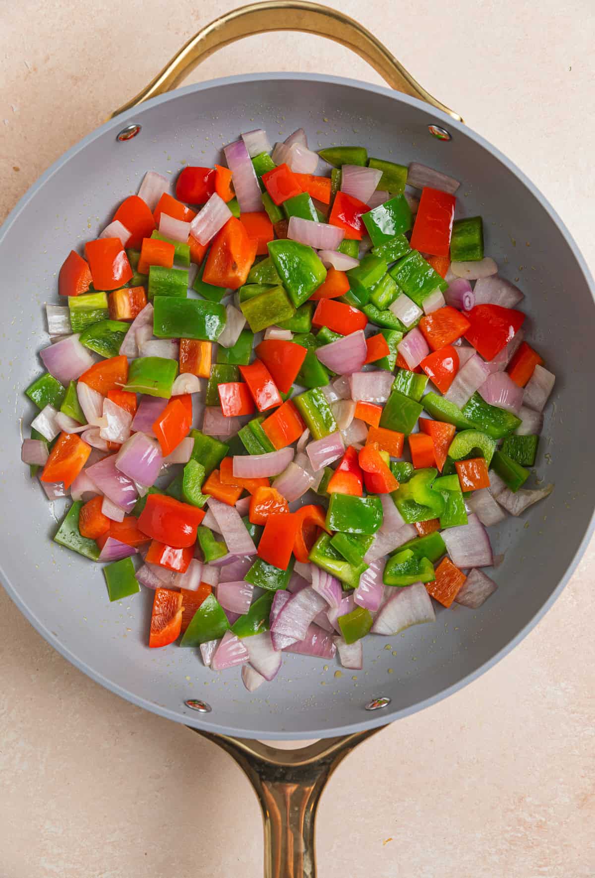 Onions and peppers sautéd in a skillet. 