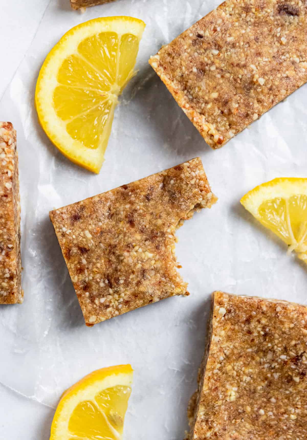 Homemade Lemon Coconut Energy Bars on parchment with fresh lemon.