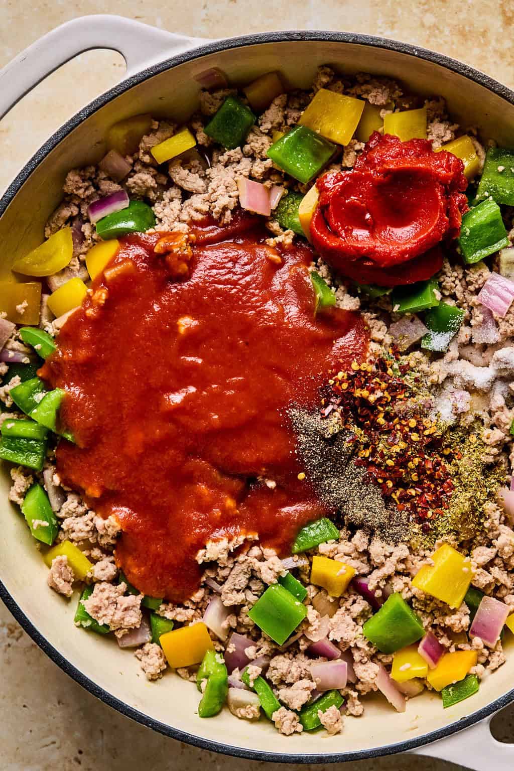Tomato sauce, tomato paste and seasonings added to pan with browned meat and peppers.