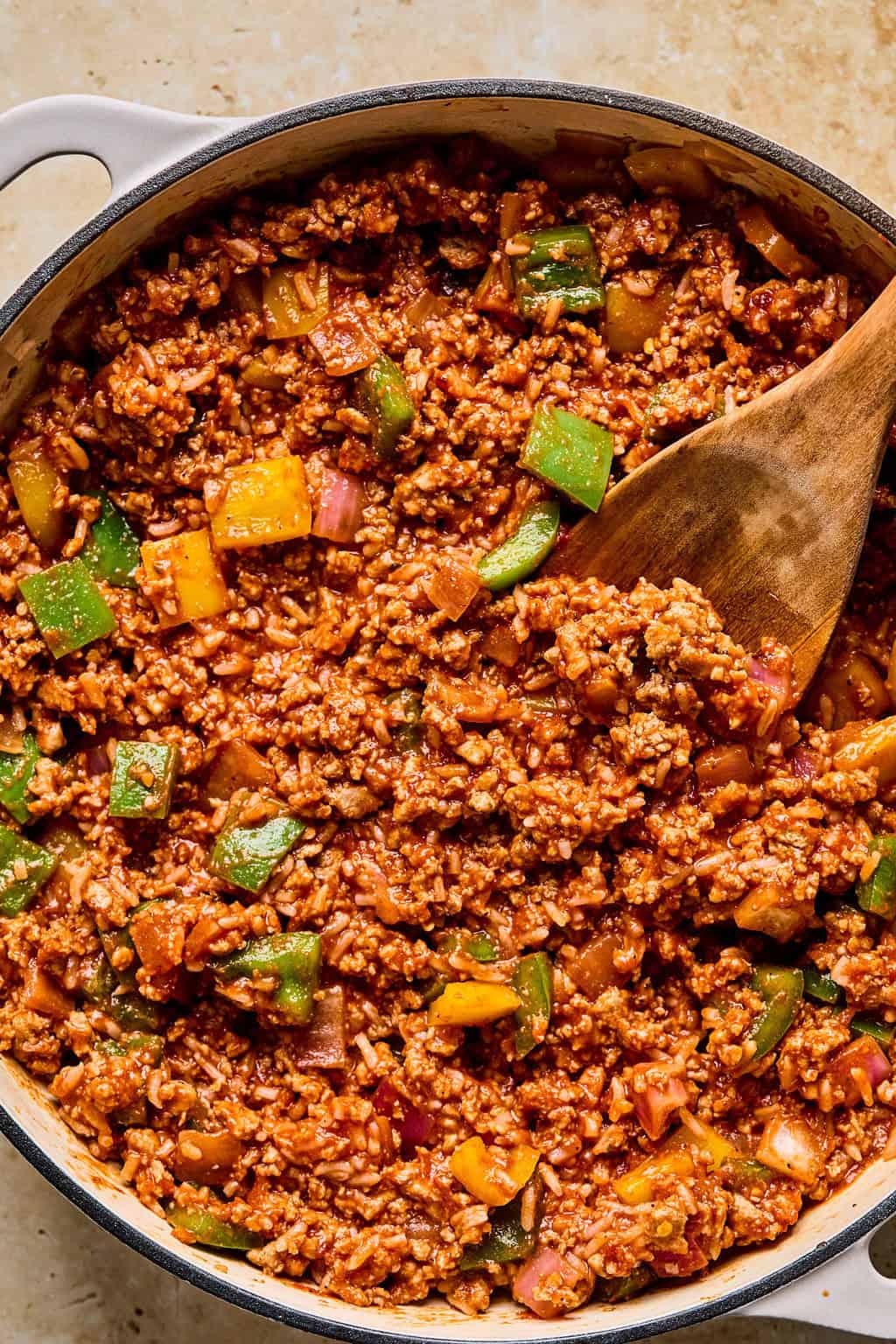 Cooked skillet dinner with wooden spoon scooping in.