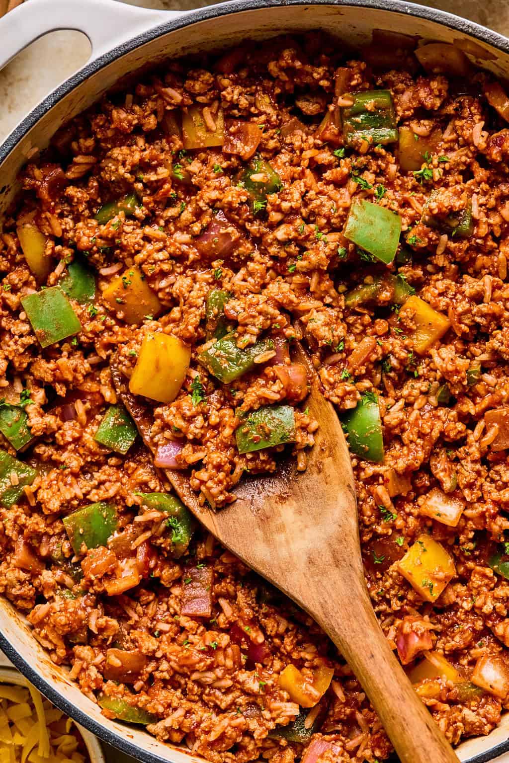 Skillet with ground turkey and pepper dinner with rice and wooden spoon scooping in.