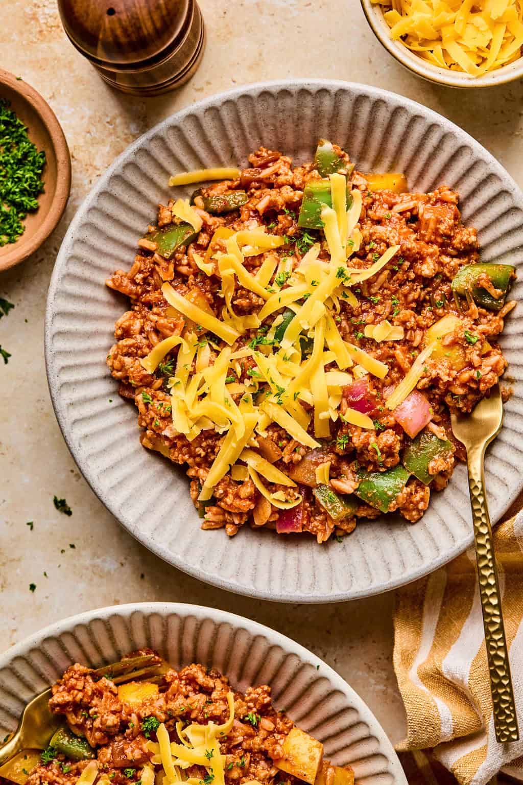 Bowl with ground turkey, pepper and rice skillet dinner topped with cheese and fork scooping into bowl.