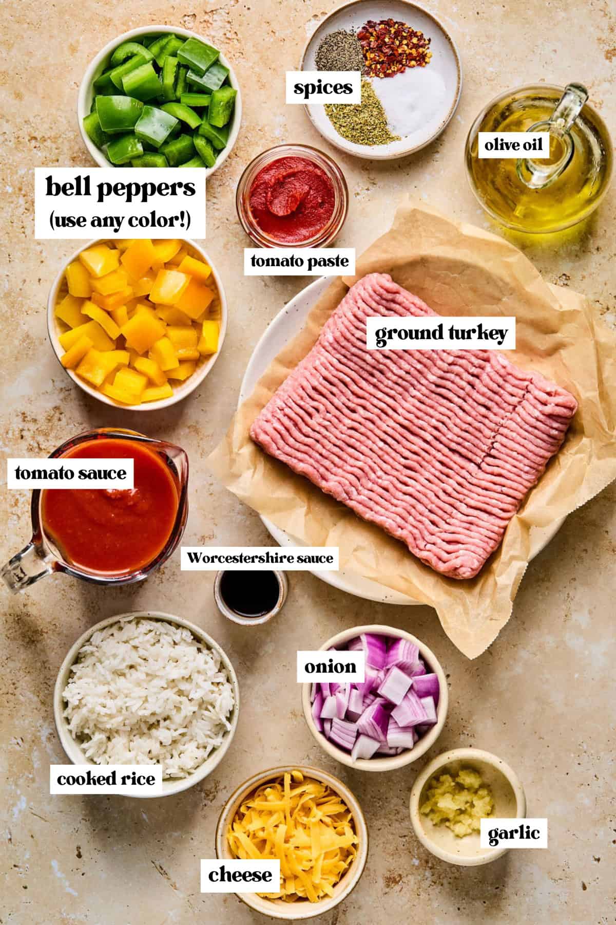 Diced bell peppers, onions, raw ground meat, and other ingredients for recipe arranged on surface.