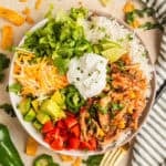Slow cooker chicken burrito bowl with rice, beans, corn, cheese, lettuce and more.