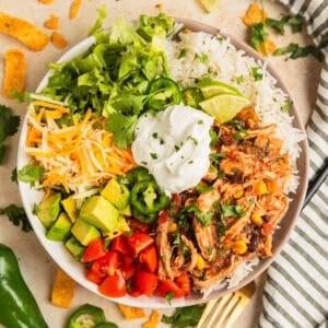 Slow cooker chicken burrito bowl with rice, beans, corn, cheese, lettuce and more.