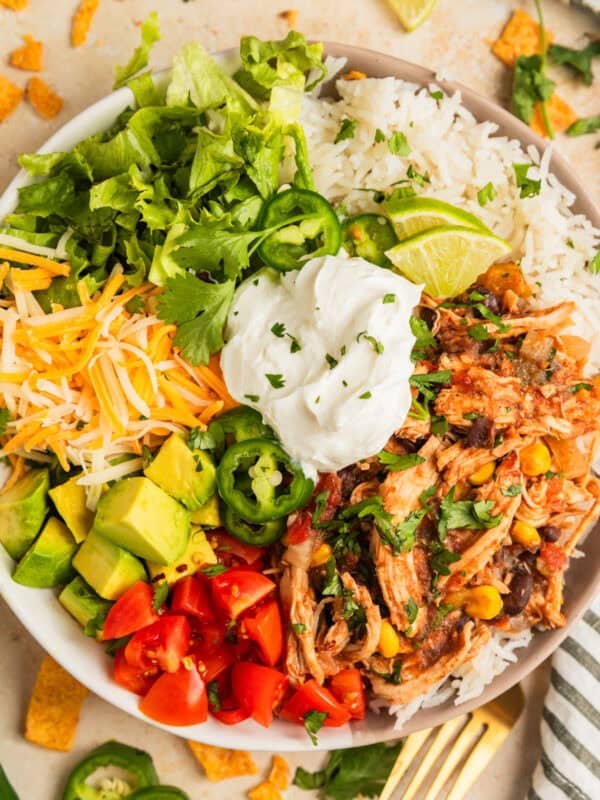 Slow cooker chicken burrito bowl with rice, beans, corn, cheese, lettuce and more.