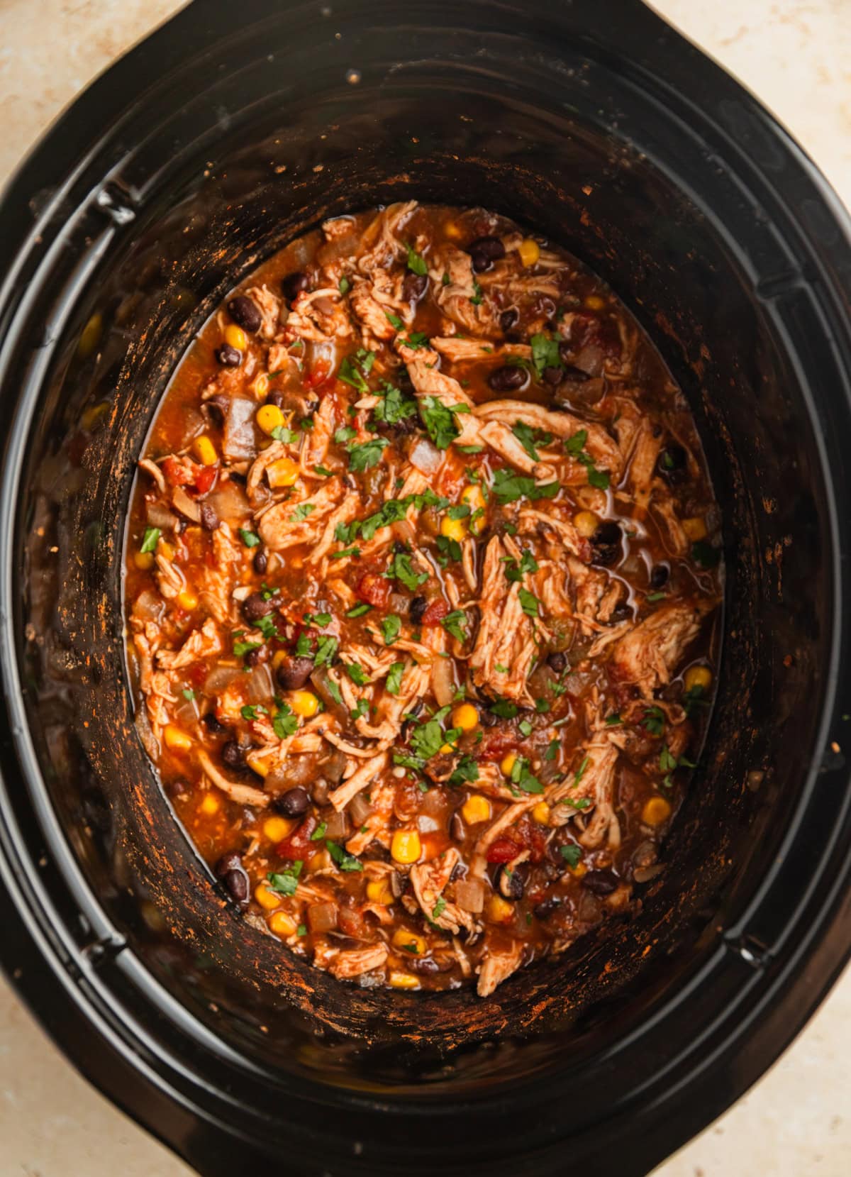 Chicken burrito mixture  in crockpot topped with chopped cilantro.