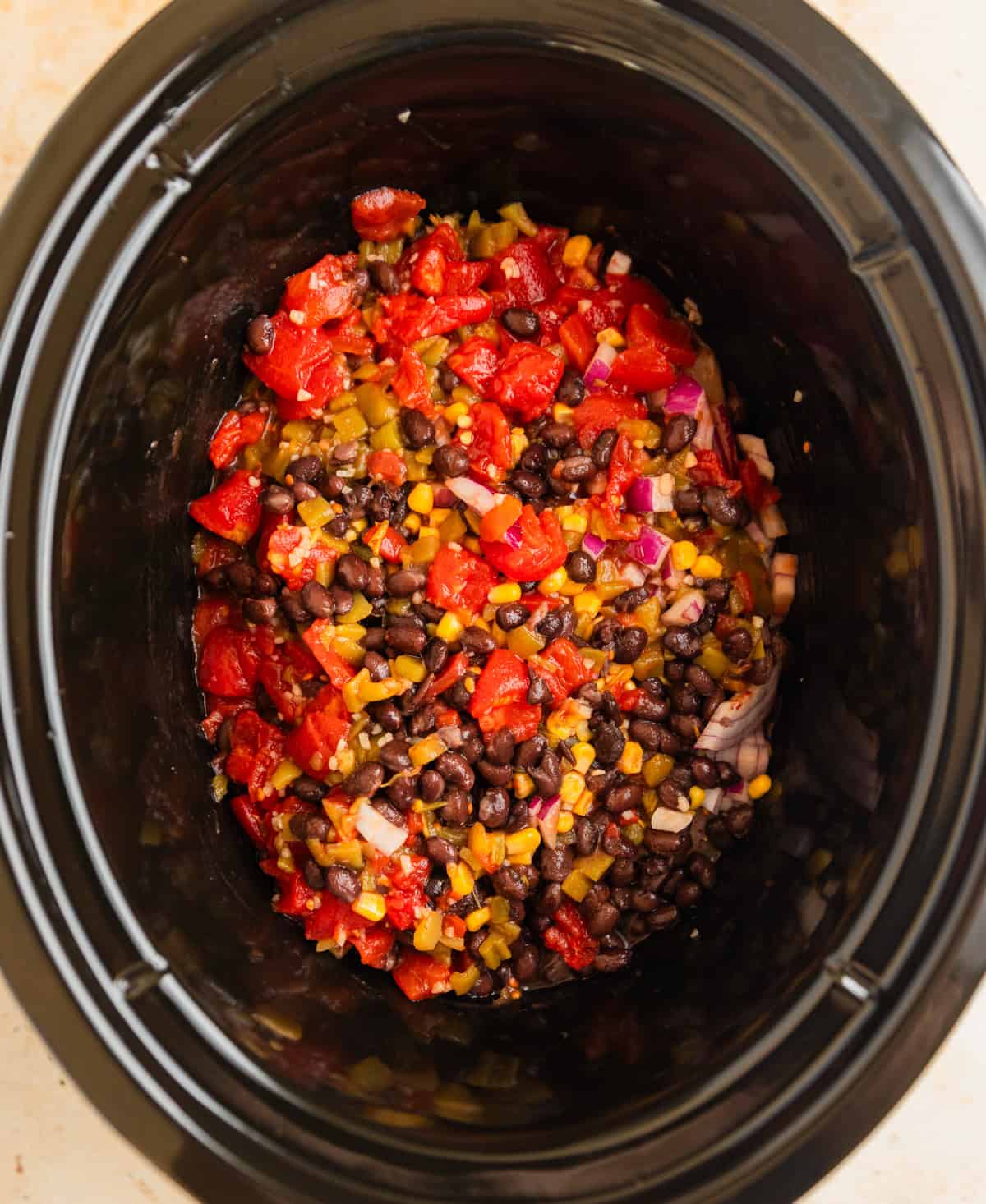 Bean, corn and tomatoes over chicken breast in slow cooker.