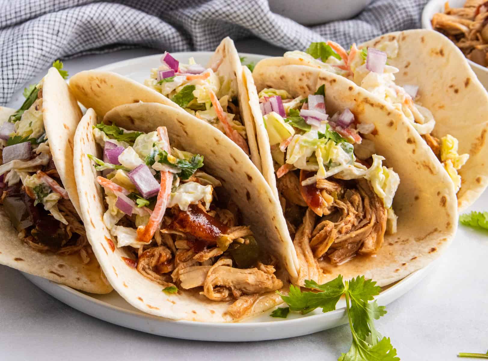 Tacos on white plate topped with slaw.