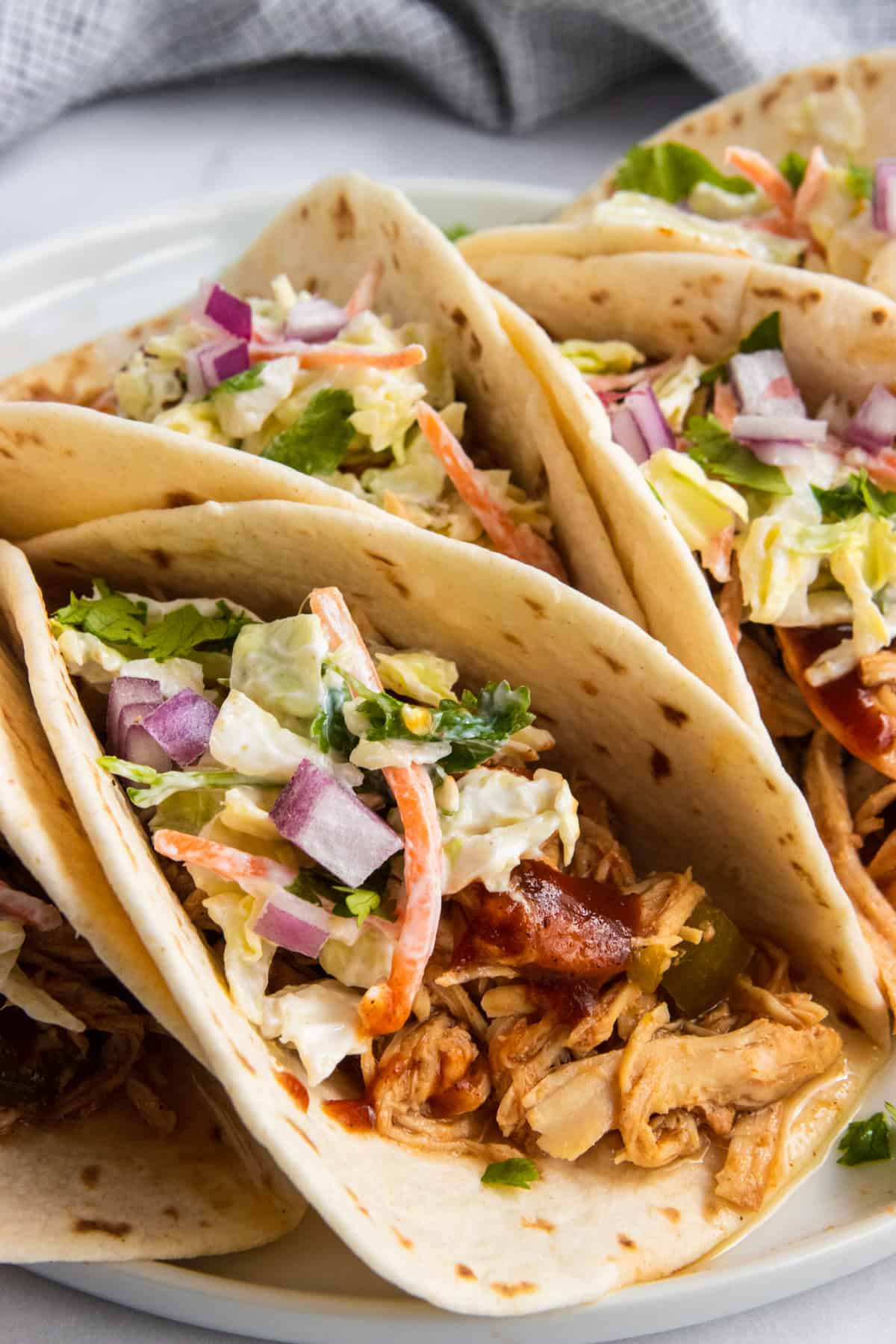 BBQ Chicken tacos with slaw and cilantro on plate.