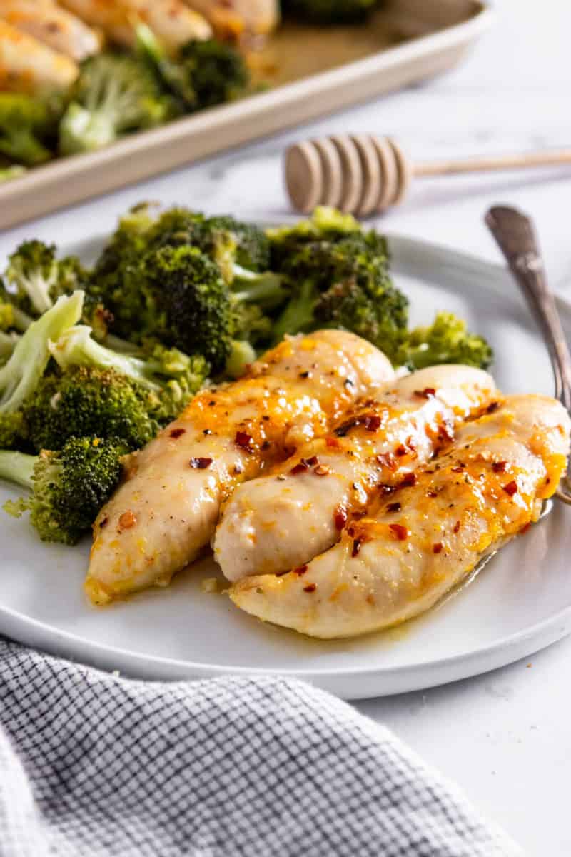 Baked orange chicken with broccoli on white plate.