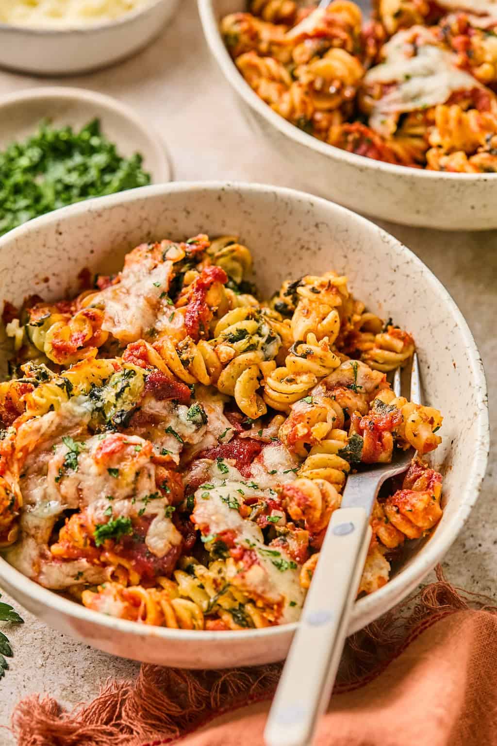 Bowl with cottage cheese, tomato and spinach baked pasta and fork propped in the bowl.