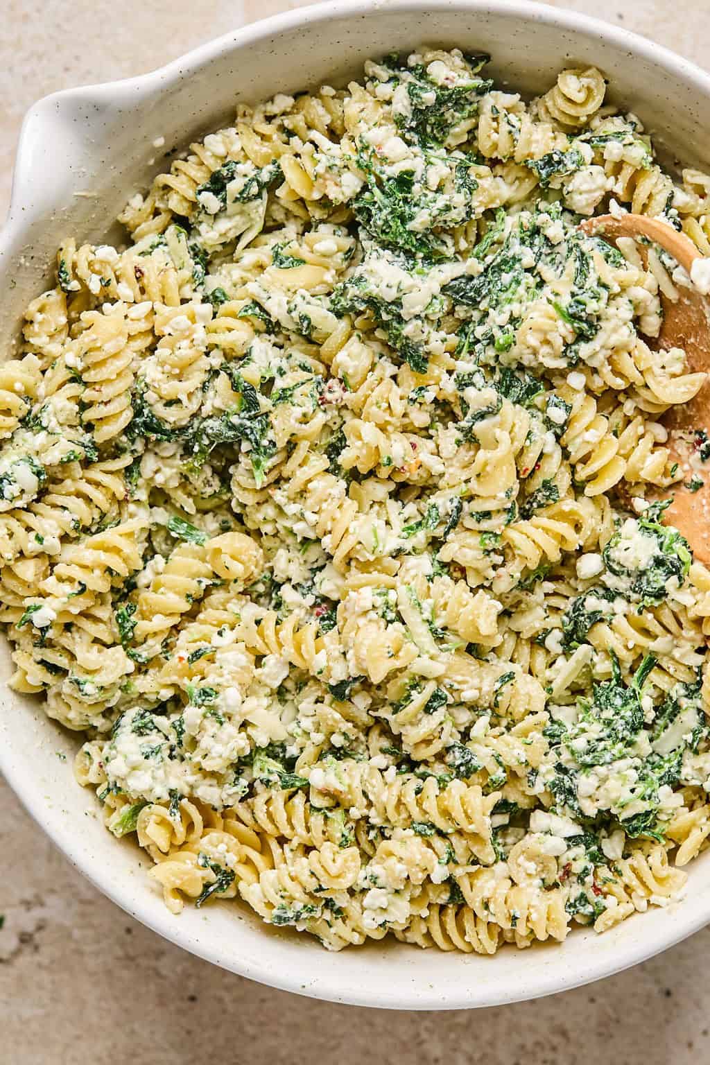 Spinach, cottage cheese mixture and pasta combined in mixing bowl.