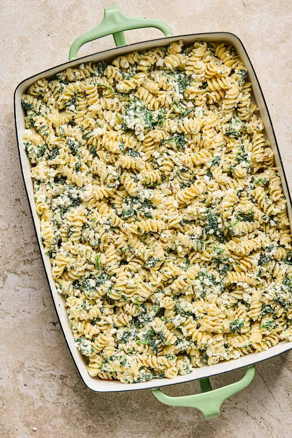 Pasta bake mixture added over marinara sauce in pan.