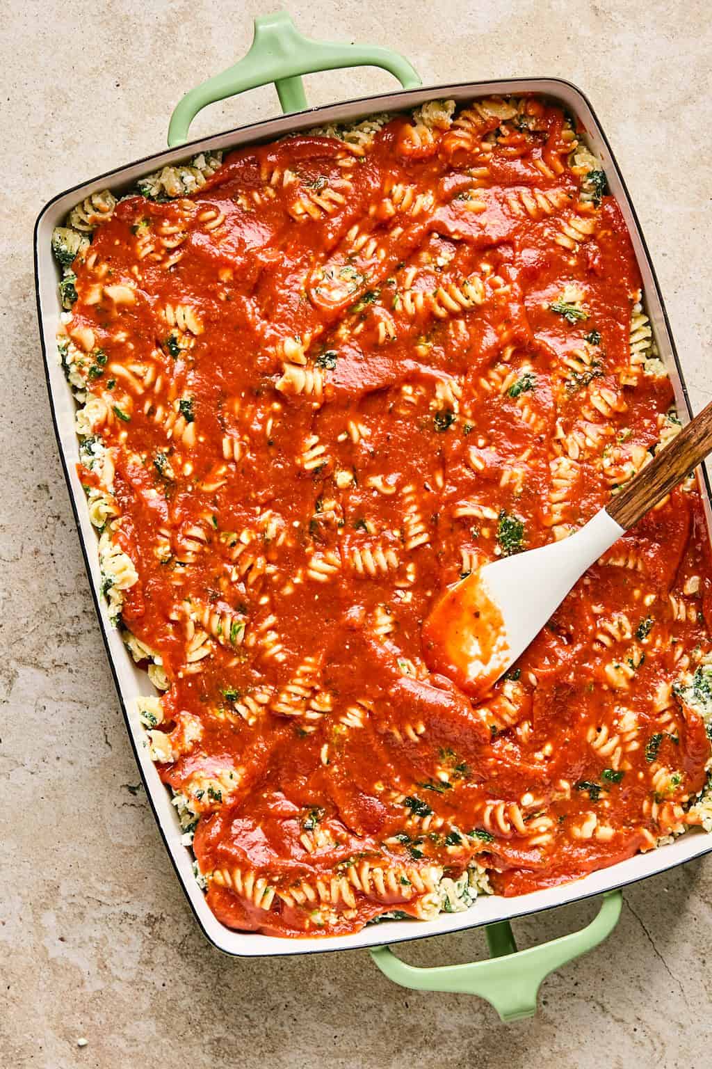 Marinara spread over top of spinach and cottage cheese pasta casserole before baking.
