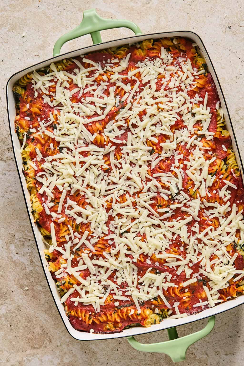 Cheese sprinkled over top of pasta bake before melting.