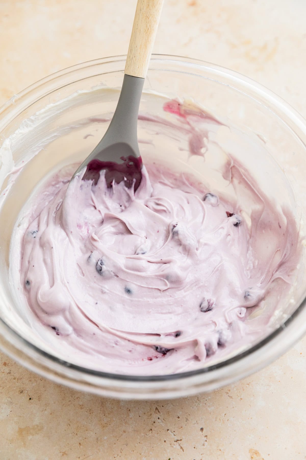 Blueberry cheesecake dip in glass bowl with spoon.
