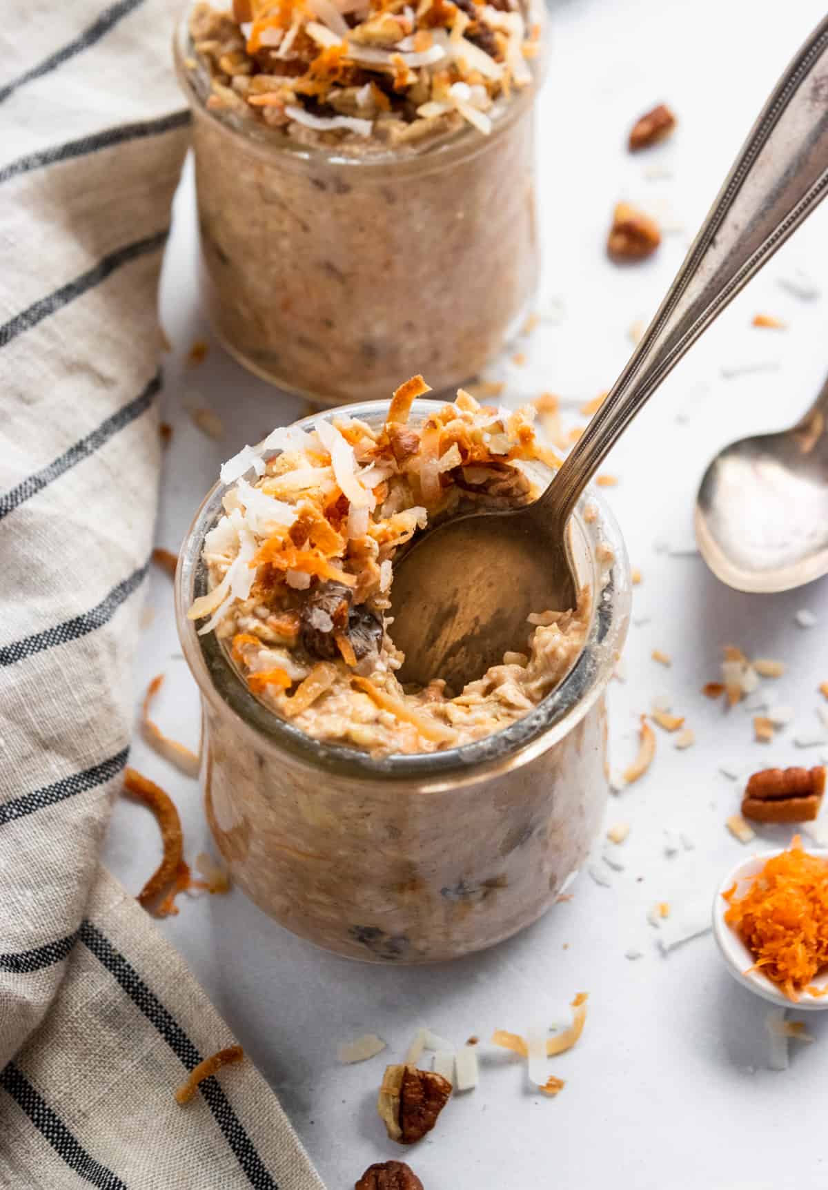 Carrot cake overnight oats in jar with spoon scooping in.