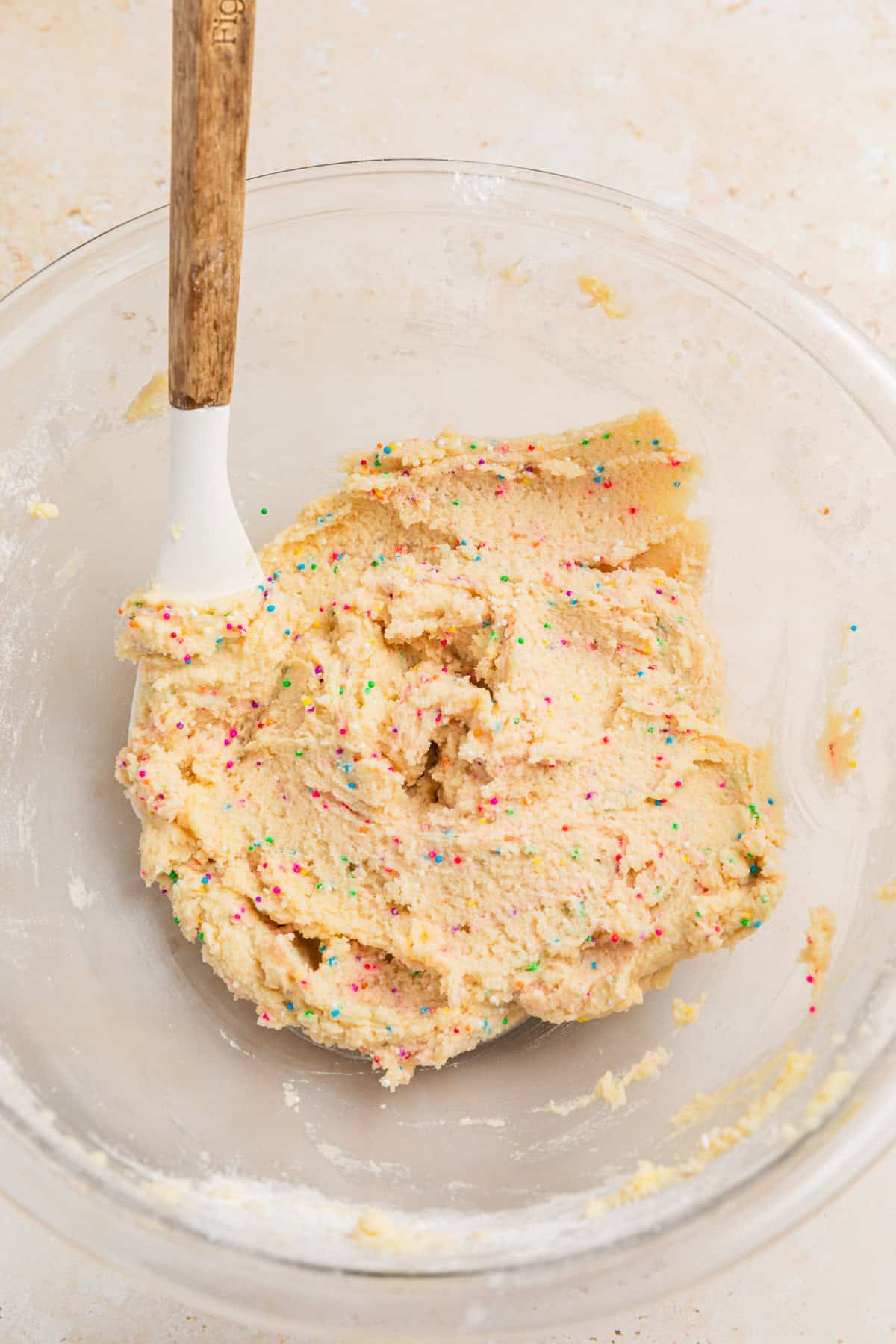Prepared sugar cookie dough with rainbow sprinkles in bowl.