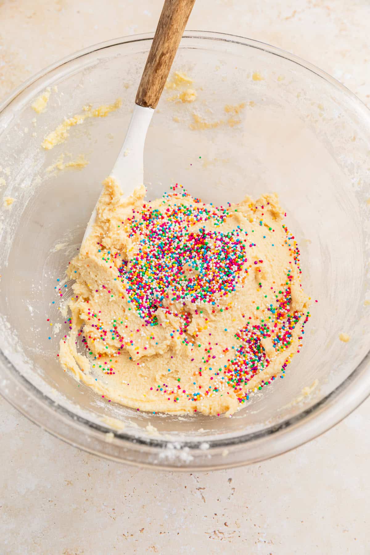Sprinkles added to edible sugar cookie dough in bowl.