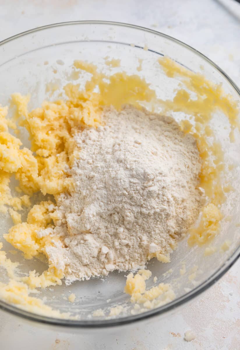Flour added to creamed butter and sugar in mixing bowl.