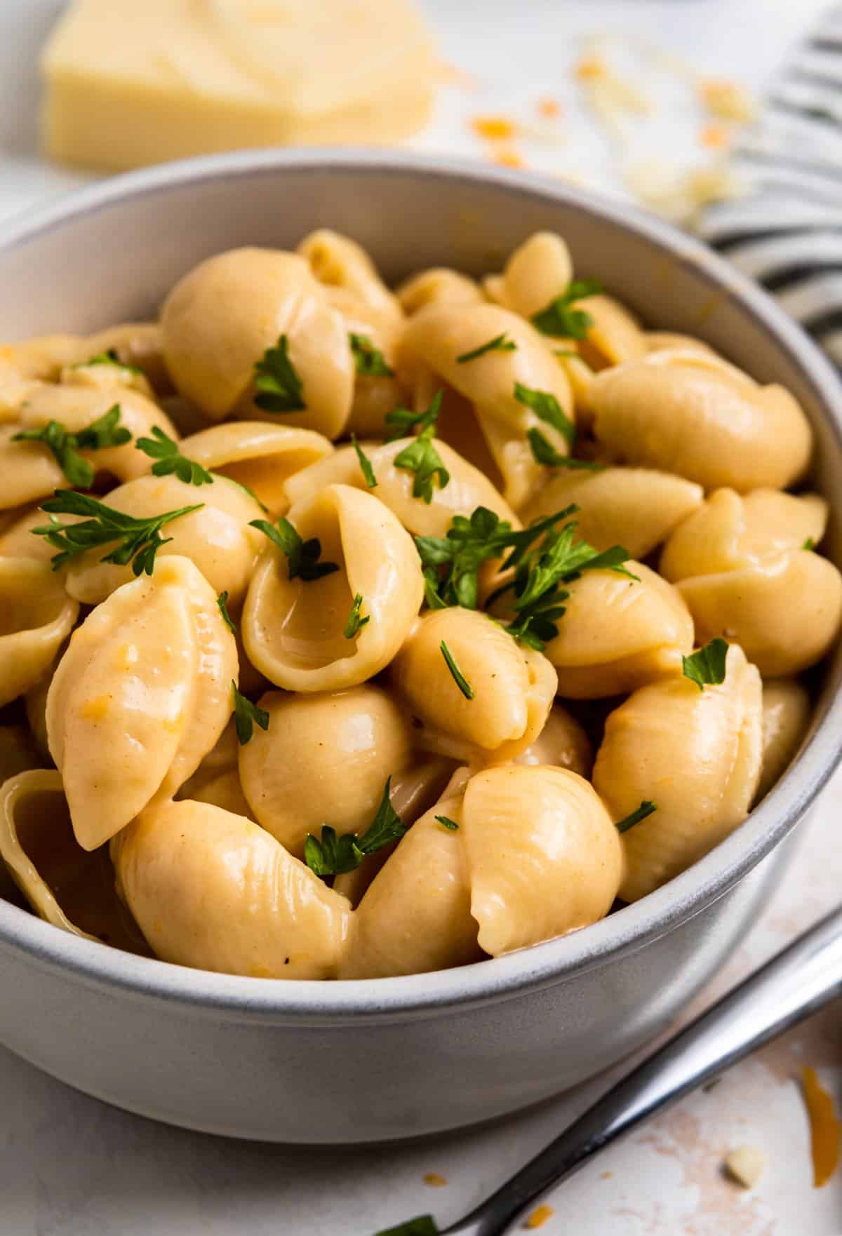 Bowl of instant pot mac and cheese shells with chopped parsley on top.