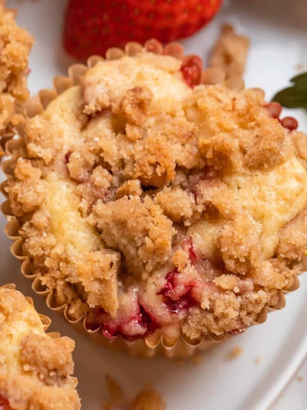 Strawberry crumble muffins on white plate with berries.