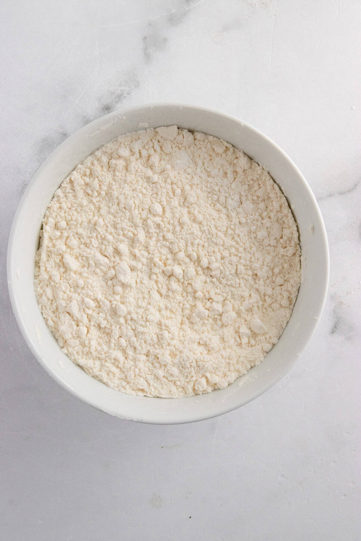 Dry ingredients for muffins whisked together in white bowl.