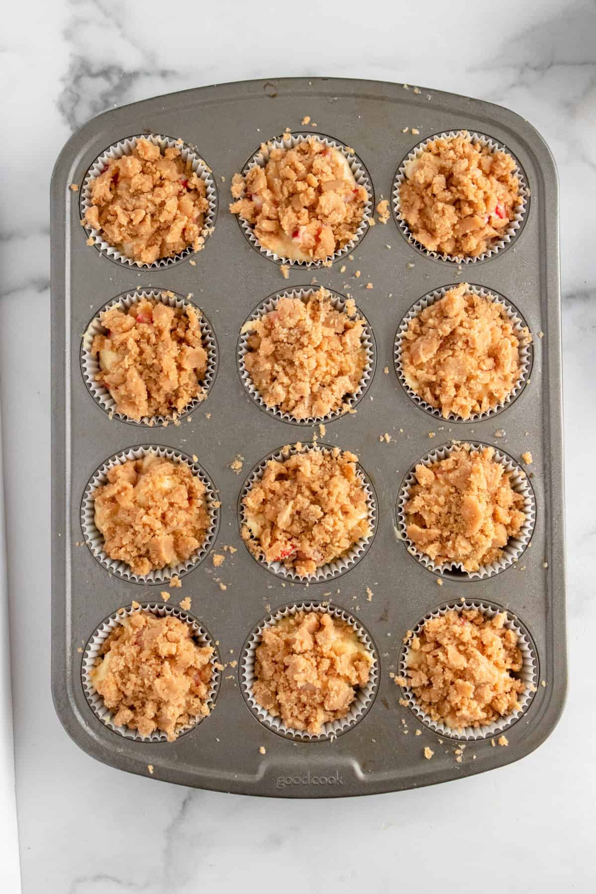 Crumble topped strawberry muffins in muffin pan before baking.