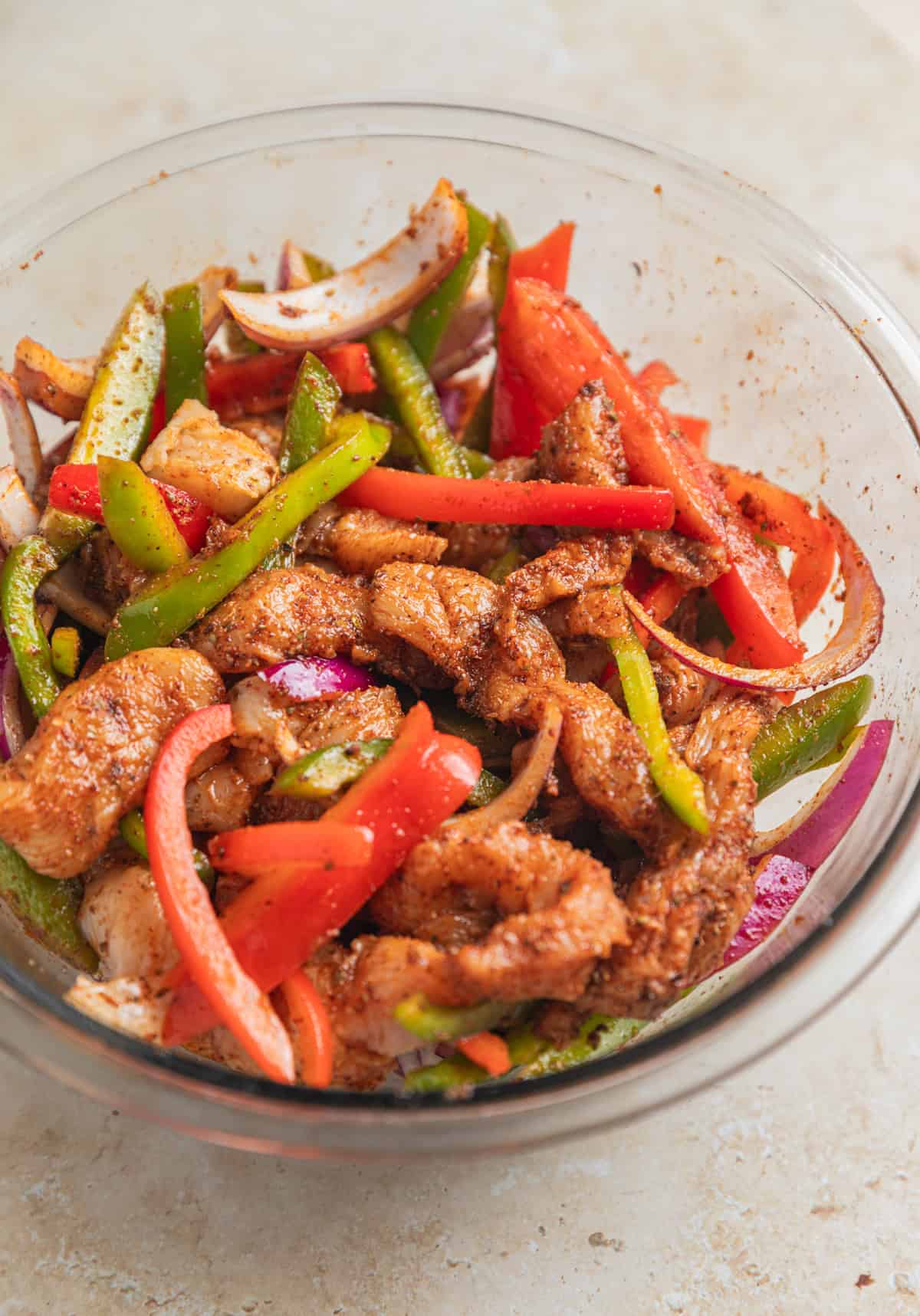 Chicken fajita mixture in bowl with marinade before being cooked.