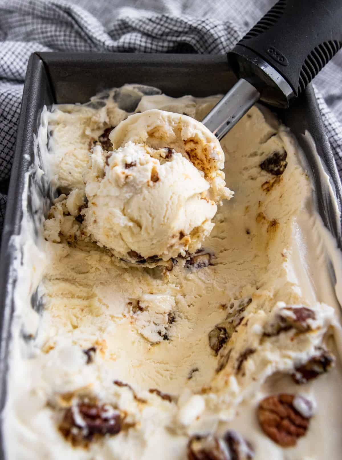 Butter pecan ice cream scooped in container.