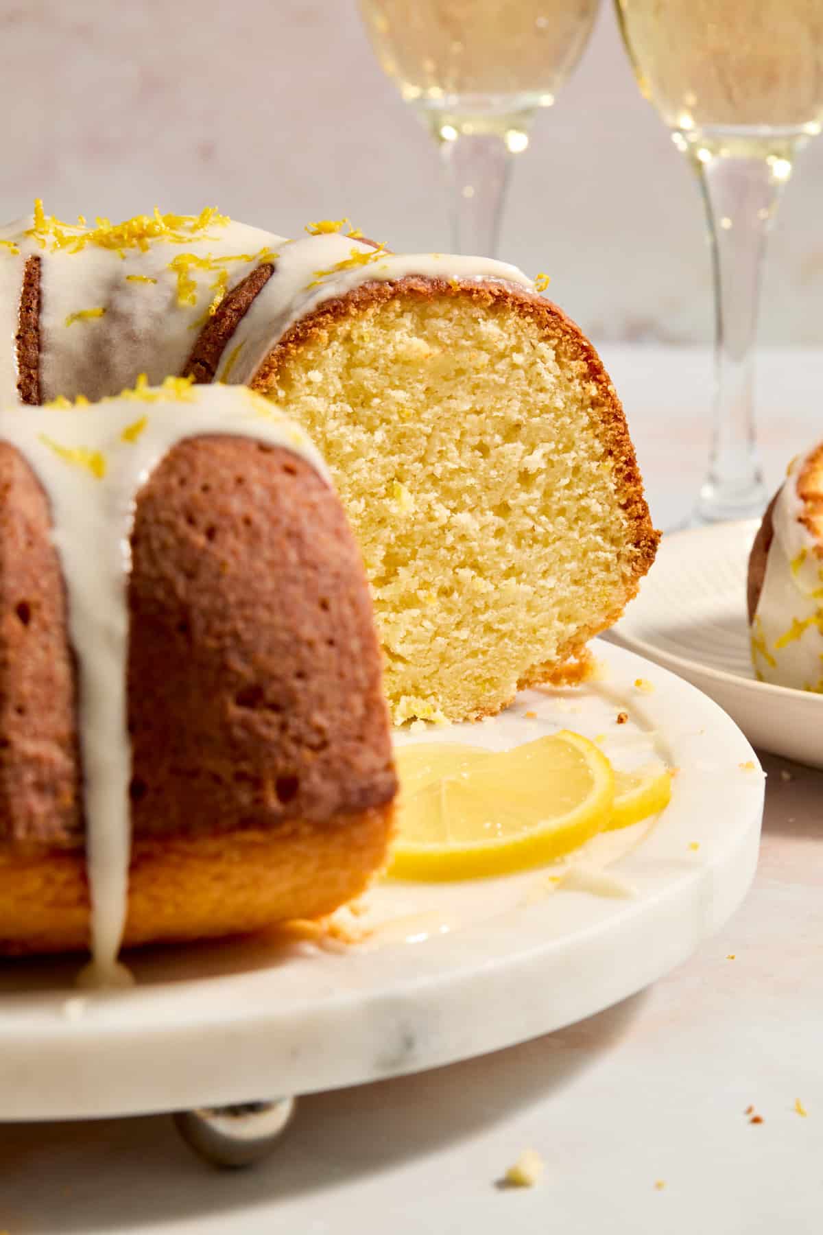 Lemon champagne bundt cake on cake tray with lemon glaze drizzled over top.