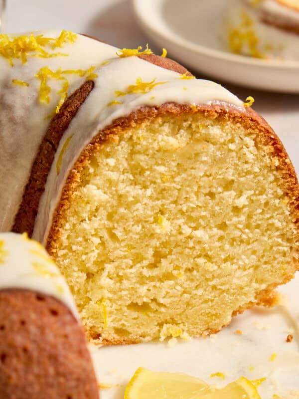 Lemon bundt cake on cake plate with slice cut out to show texture of cake.