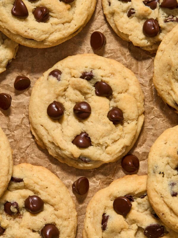 Chocolate chip cookies arranged on brown parchment paper with chocolate chips.