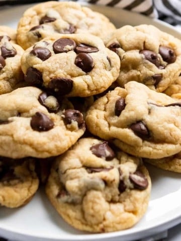 Chocolate chip cookies arranged on white plate.
