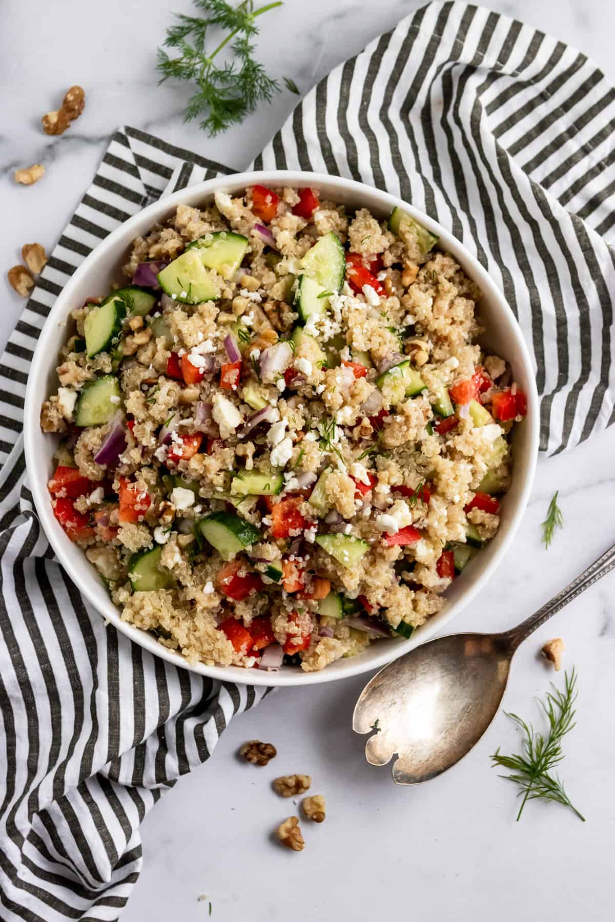 Feta quinoa salad in bowl with serving spoon.